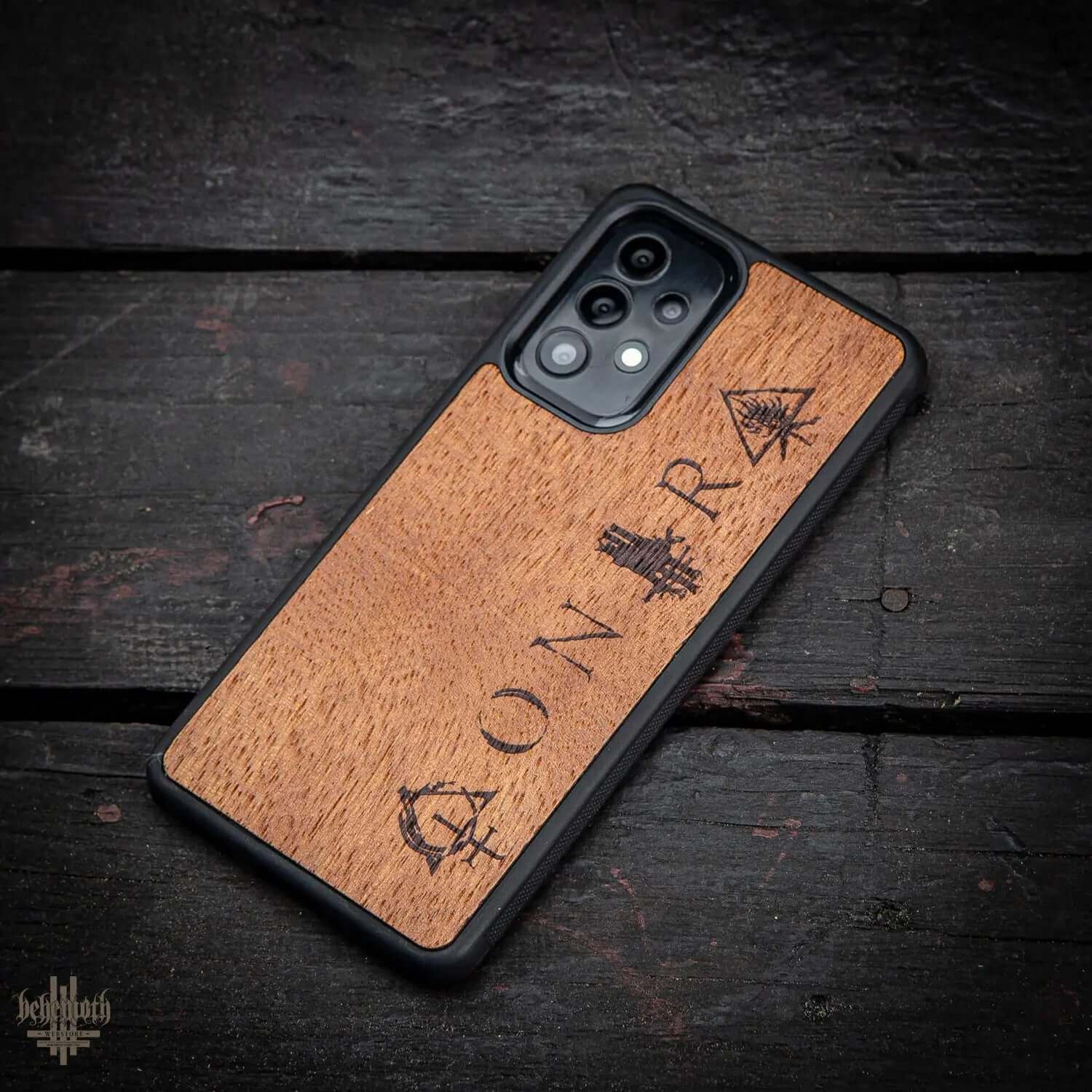 Samsung Galaxy A52 case with merbau wood finish and Behemoth 'CONTRA' logo on dark wood surface.