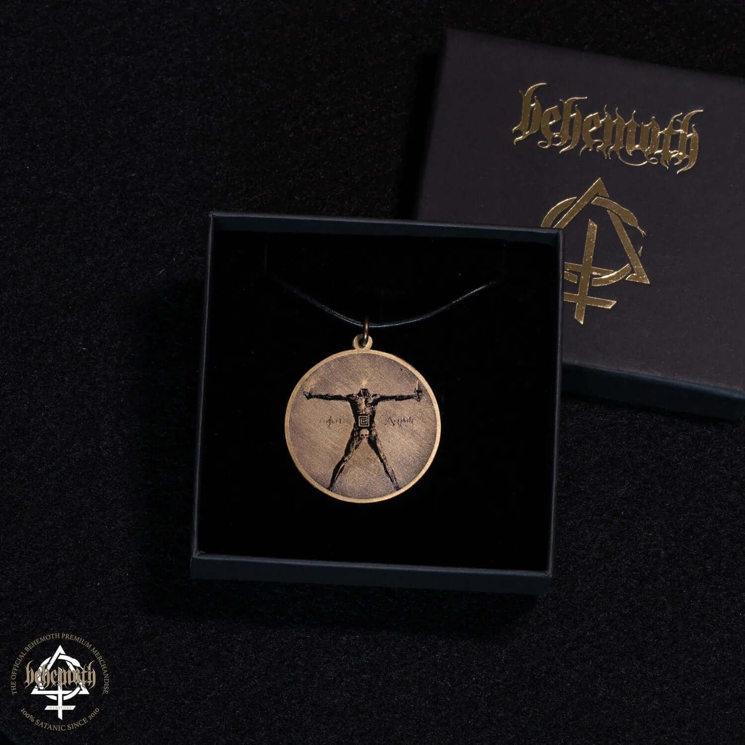 Behemoth 'Akephale' patinated brass necklace in open box, black strap, diameter 4 cm. Gothic style with symbolic engraving.