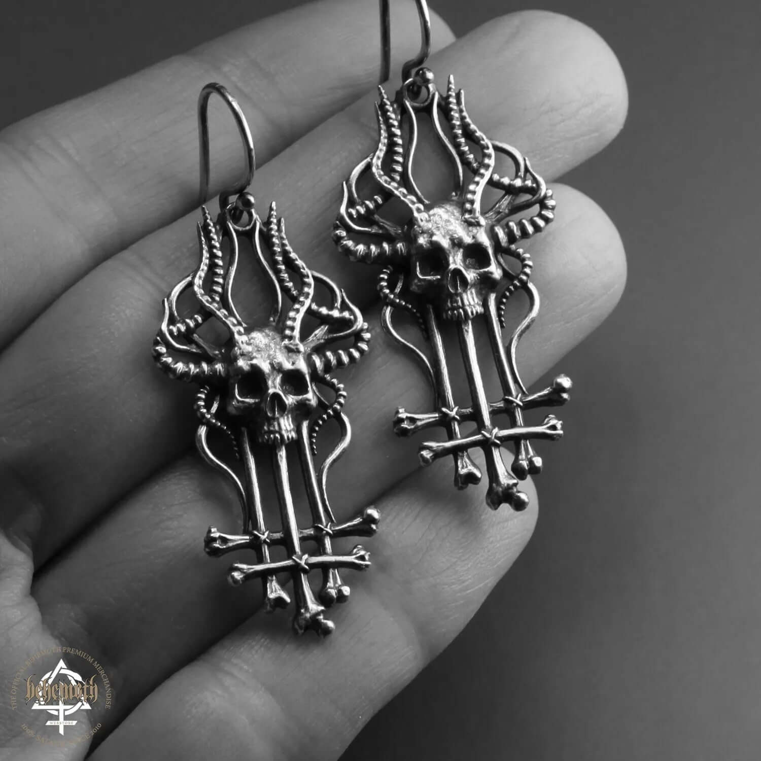 Sterling silver 'In Absentia Dei' Behemoth earrings with skull and crossbones design, handcrafted, oxidized, and polished for detail.