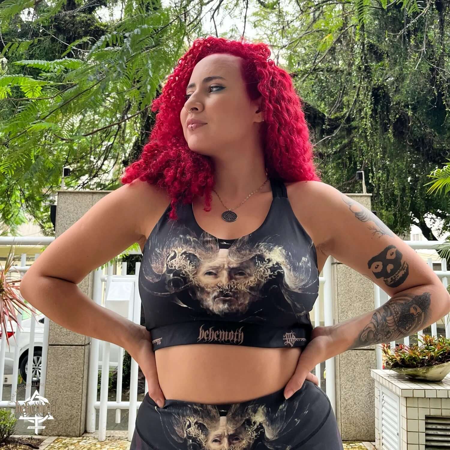 Woman wearing Behemoth 'The Satanist' sports bra with art by Dani Batista, ideal for running, gym, and yoga, featuring stable straps.