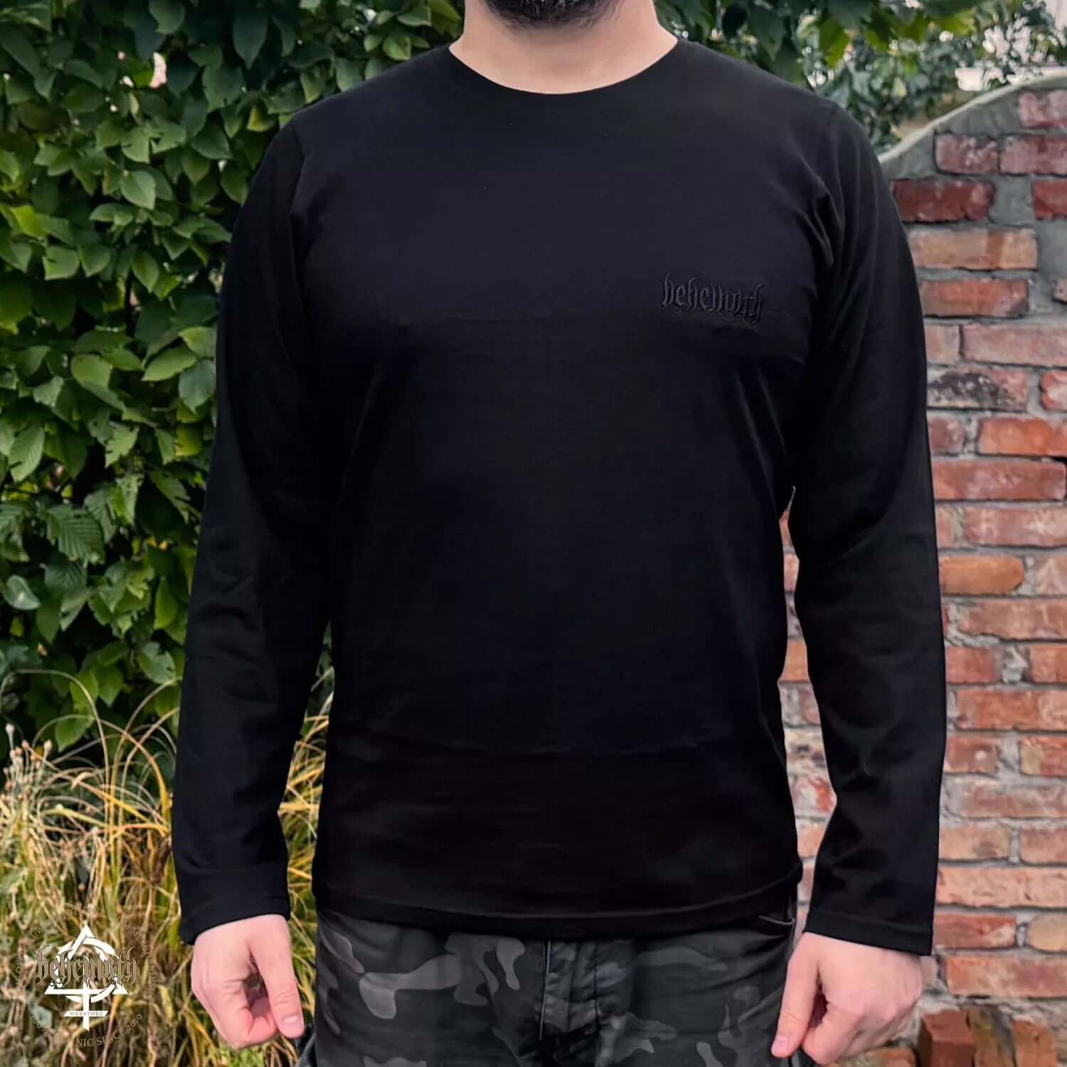 Model wearing black Behemoth 'Logo' long sleeve shirt, featuring embroidered chest logo, part of BOTB collection, premium quality.