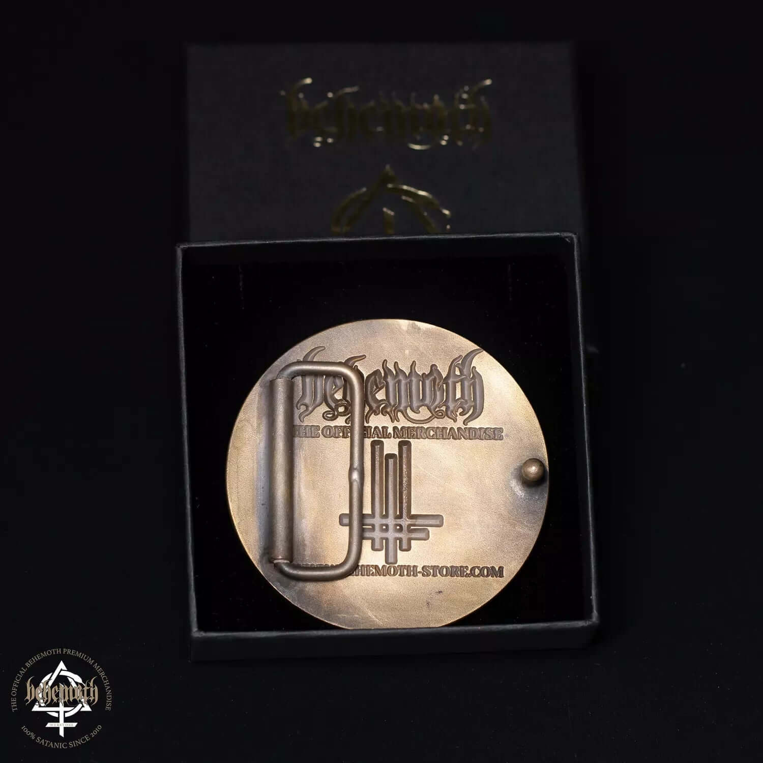 Behemoth 'Contra' brass belt buckle with engravings, black epoxy resin background, premium handcrafted in Poland, back view in box.