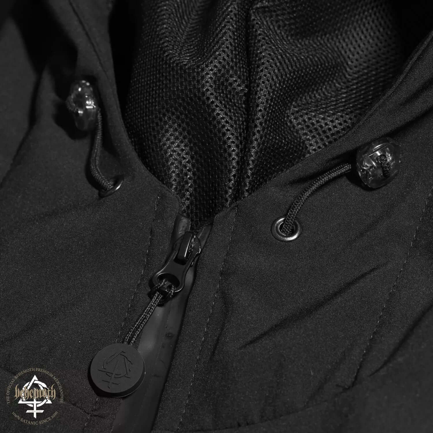 Close-up of Behemoth Logo softshell jacket's zipper, featuring black branded zip pullers and detailed fabric texture in Poland.