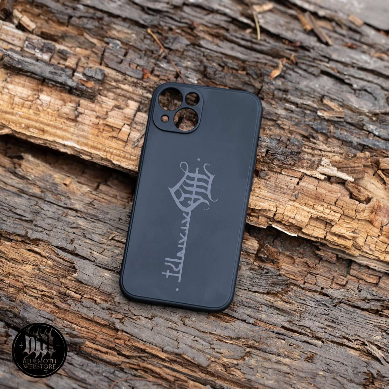 Behemoth 'The Satanist' phone case with black matte finish and glossy key sigil on a rustic wood background.