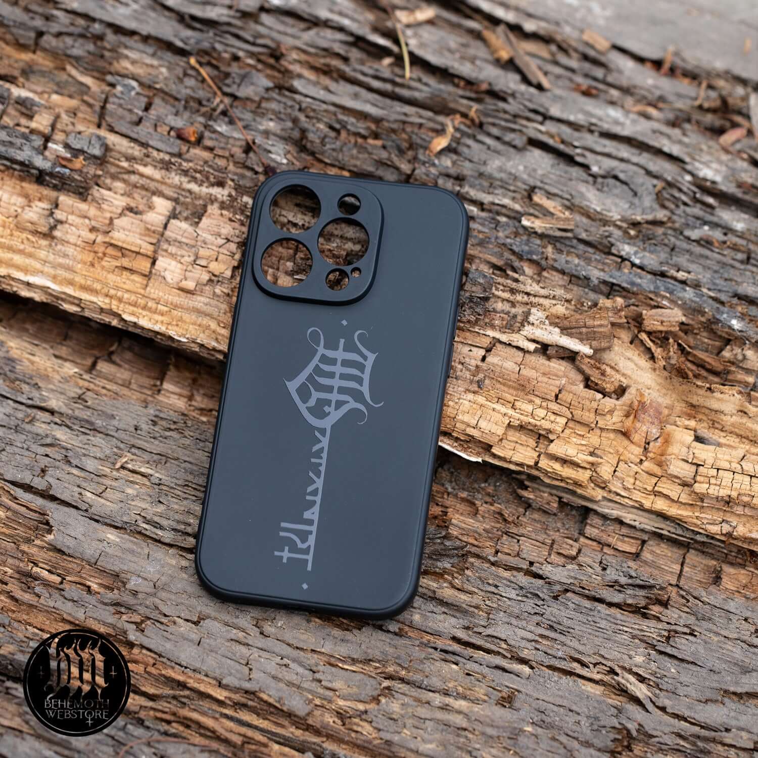 Behemoth 'The Satanist' phone case with black matte finish and key sigil design, resting on a wooden surface.