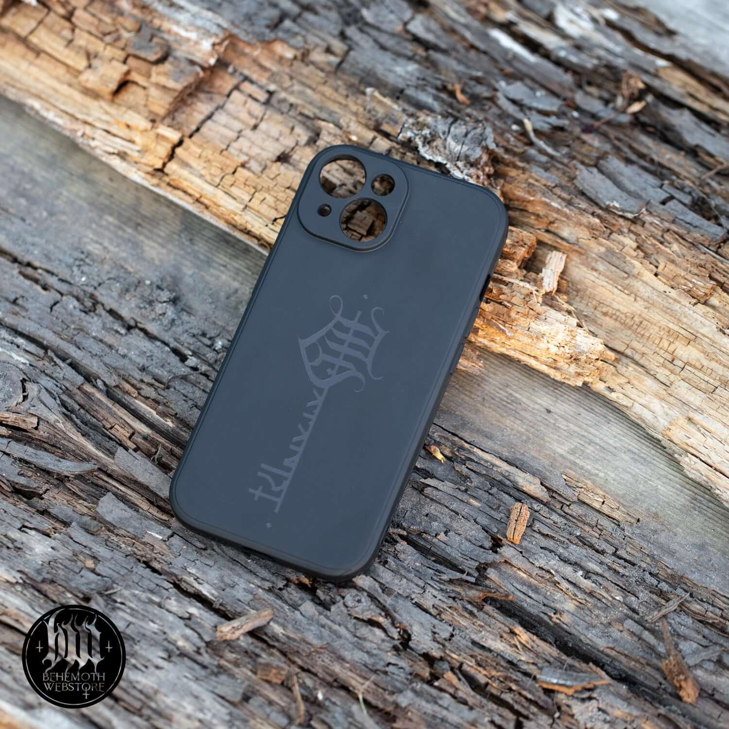 Black silicone phone case with Behemoth 'The Satanist' Key Sigil design, matte finish, on rustic wood surface.