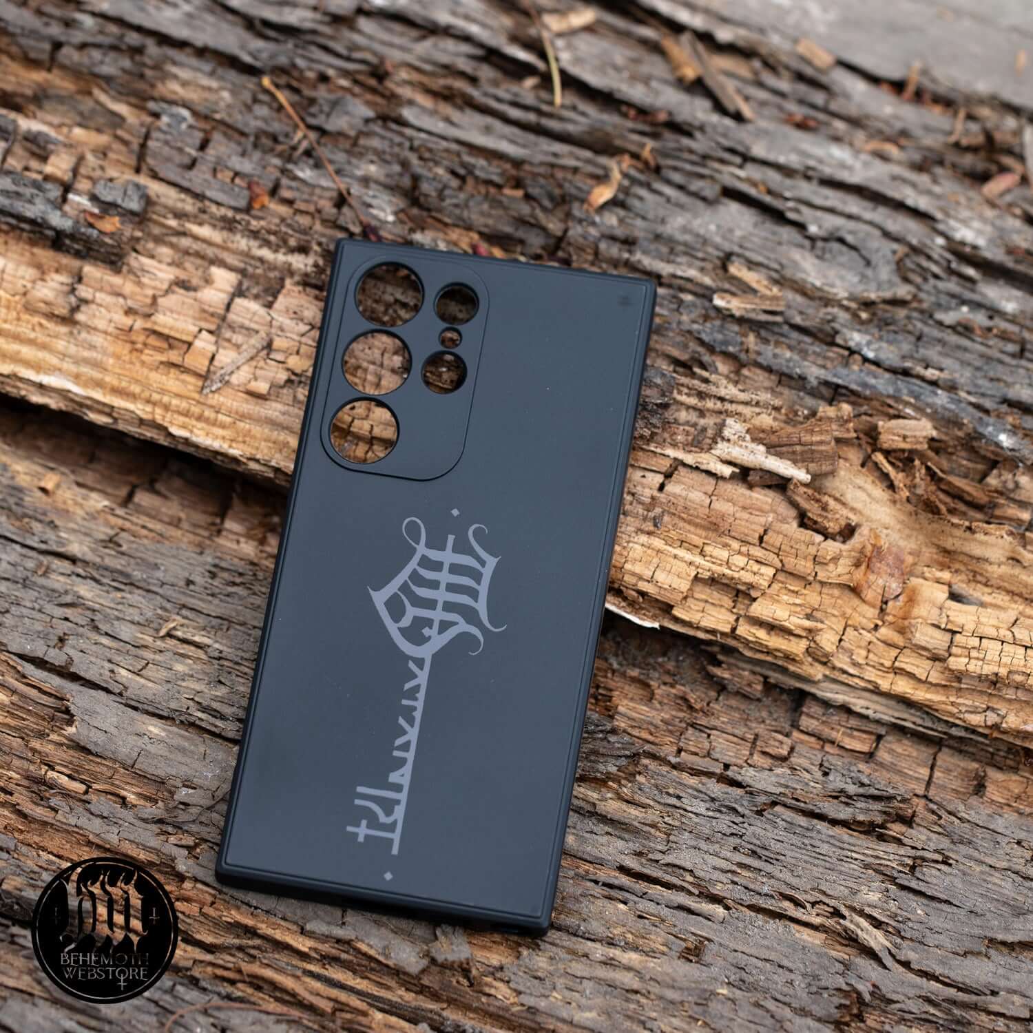 Black matte finish Behemoth 'The Satanist' phone case with key sigil on wooden background; durable silicone for optimal phone protection.