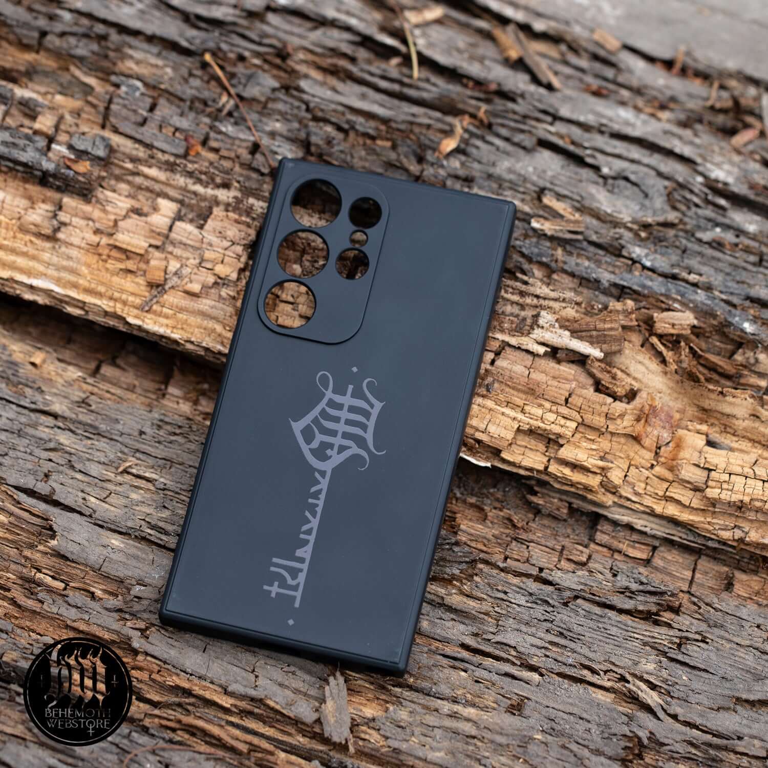 Behemoth 'The Satanist' phone case on rustic wood, showcasing glossy black Key Sigil design. Stylish, durable silicone case for phone protection.