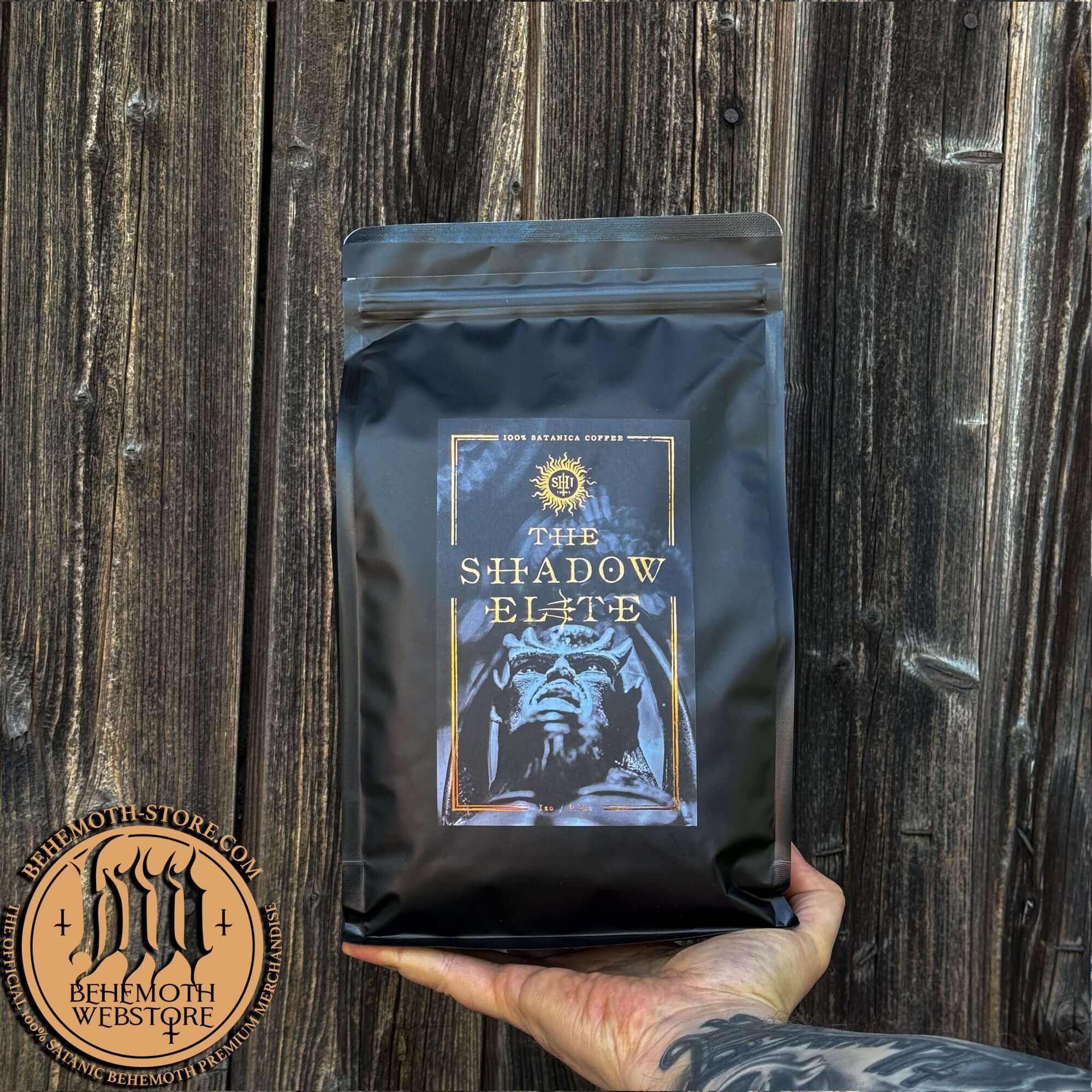 The Shadow Elite whole bean specialty coffee by Behemoth displayed in hand against wooden background.