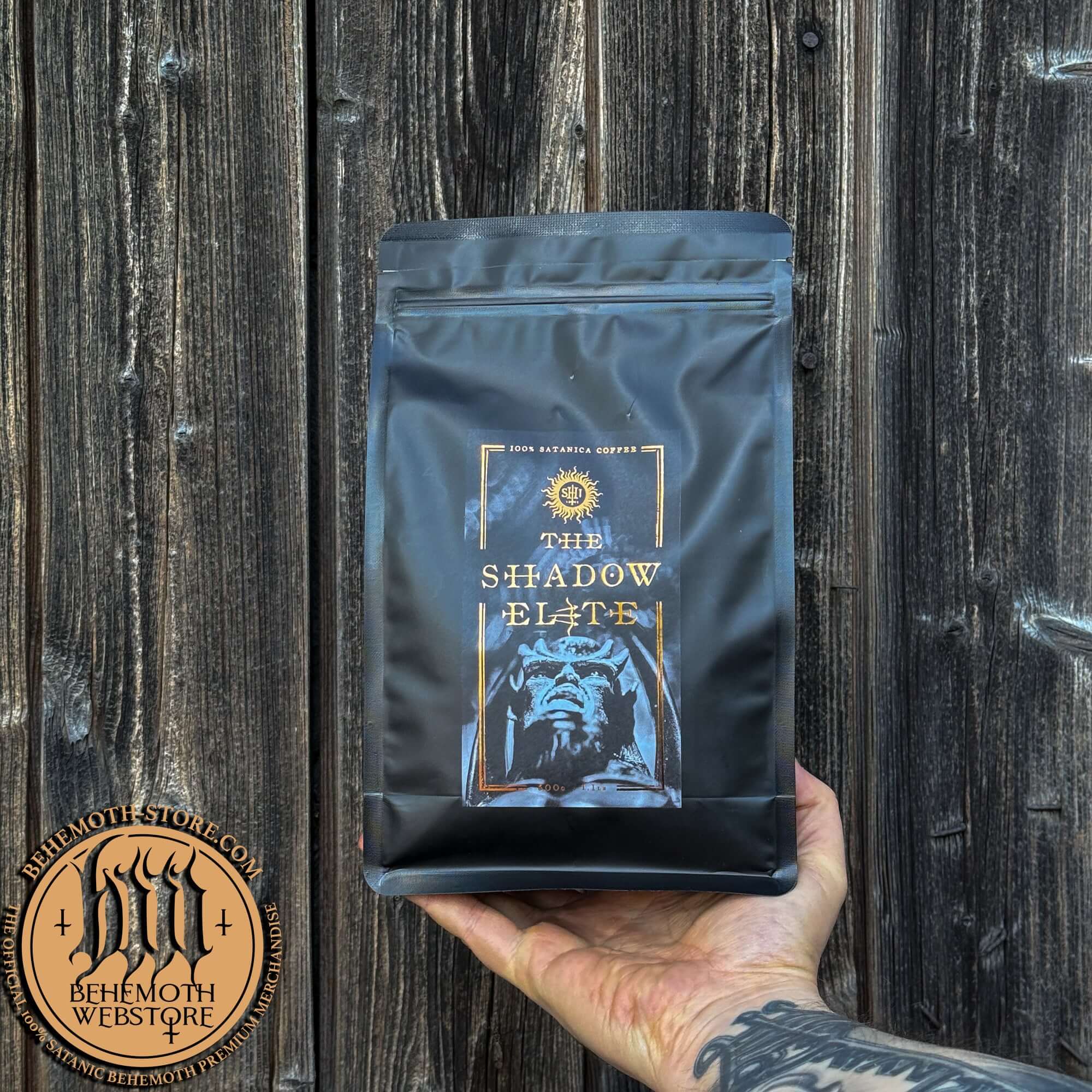 The Shadow Elite Behemoth specialty coffee whole beans package held against a wooden backdrop