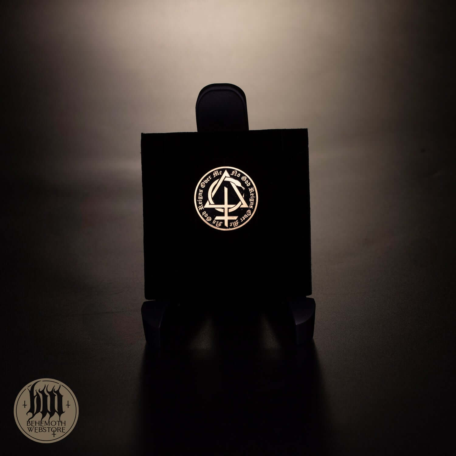 Behemoth 'Contra' patinated brass pin displayed on a stand, 3 cm diameter, featuring intricate design and dark finish.