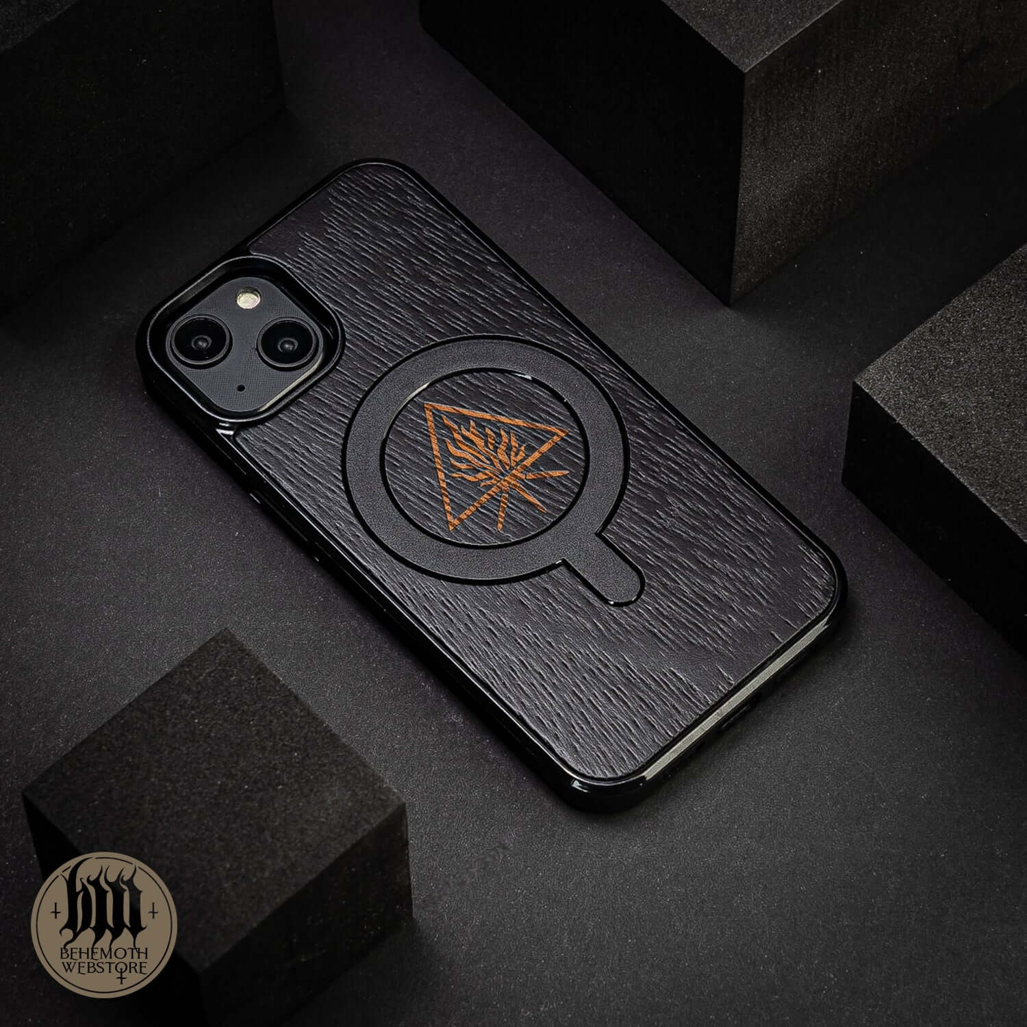 Behemoth 'The Unholy Trinity' black wooden MagSafe phone case with silicone TPU, hand-finished oak design, on textured surface.