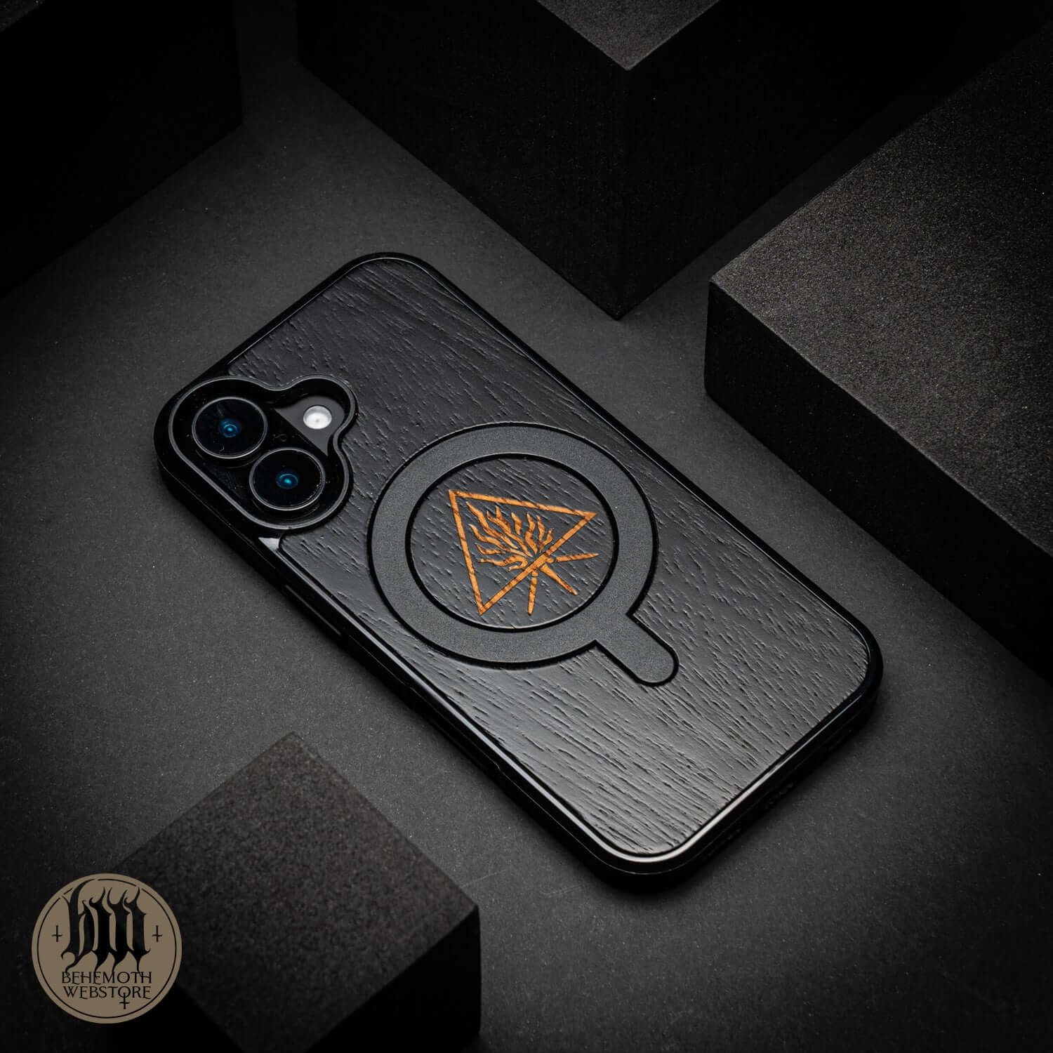 Behemoth 'The Unholy Trinity' black wooden MagSafe phone case on black background, showcasing precision craftsmanship.