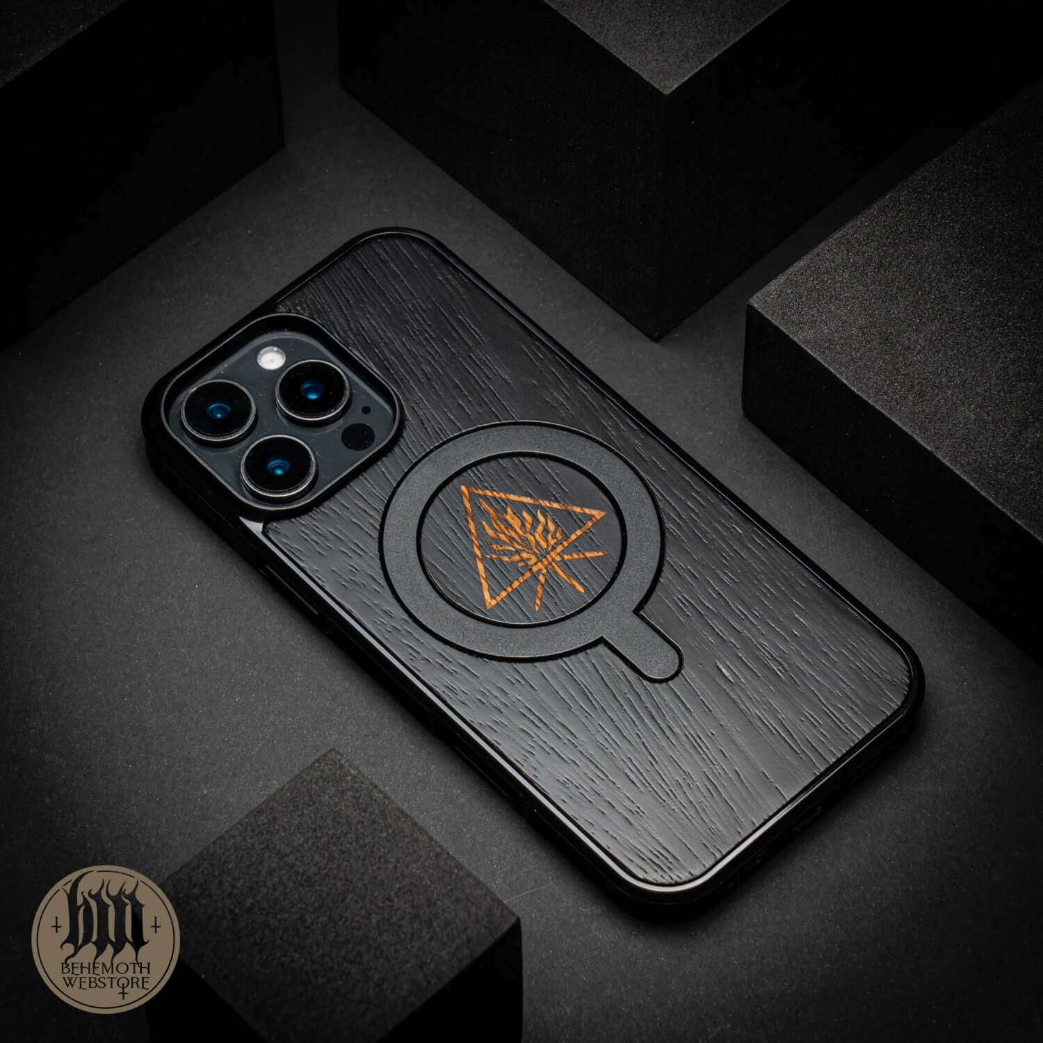 Behemoth 'The Unholy Trinity' MagSafe phone case in black oak wood and silicone, hand-finished, showing unique design.