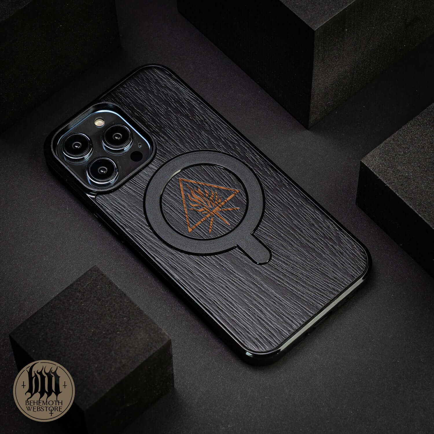 Black wooden and silicone MagSafe phone case with Behemoth 'The Unholy Trinity' design on textured oak finish