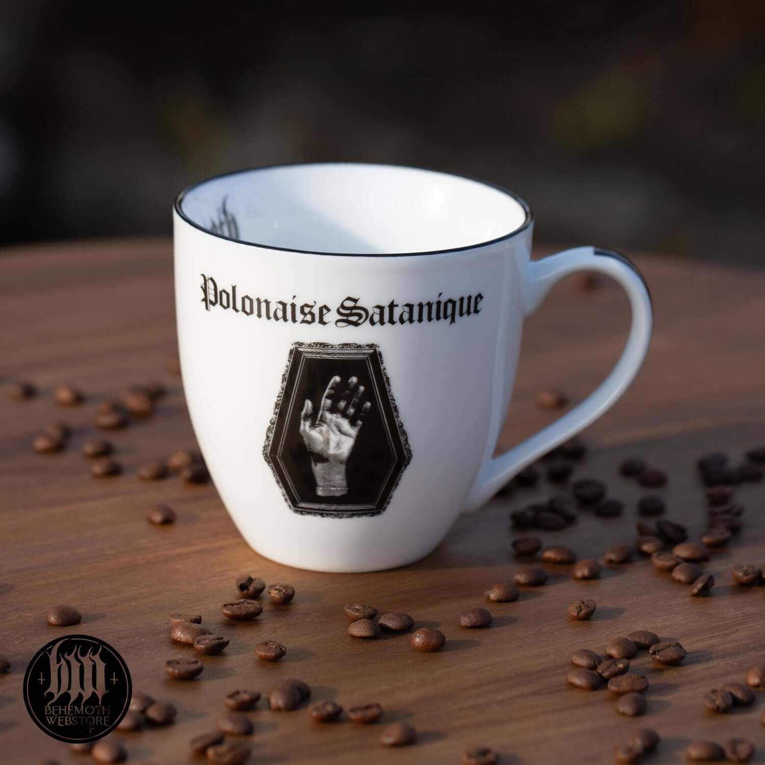 Behemoth 'Polonaise Satanique' white ceramic mug with gothic design and coffee beans on a wooden table, perfect for music enthusiasts.