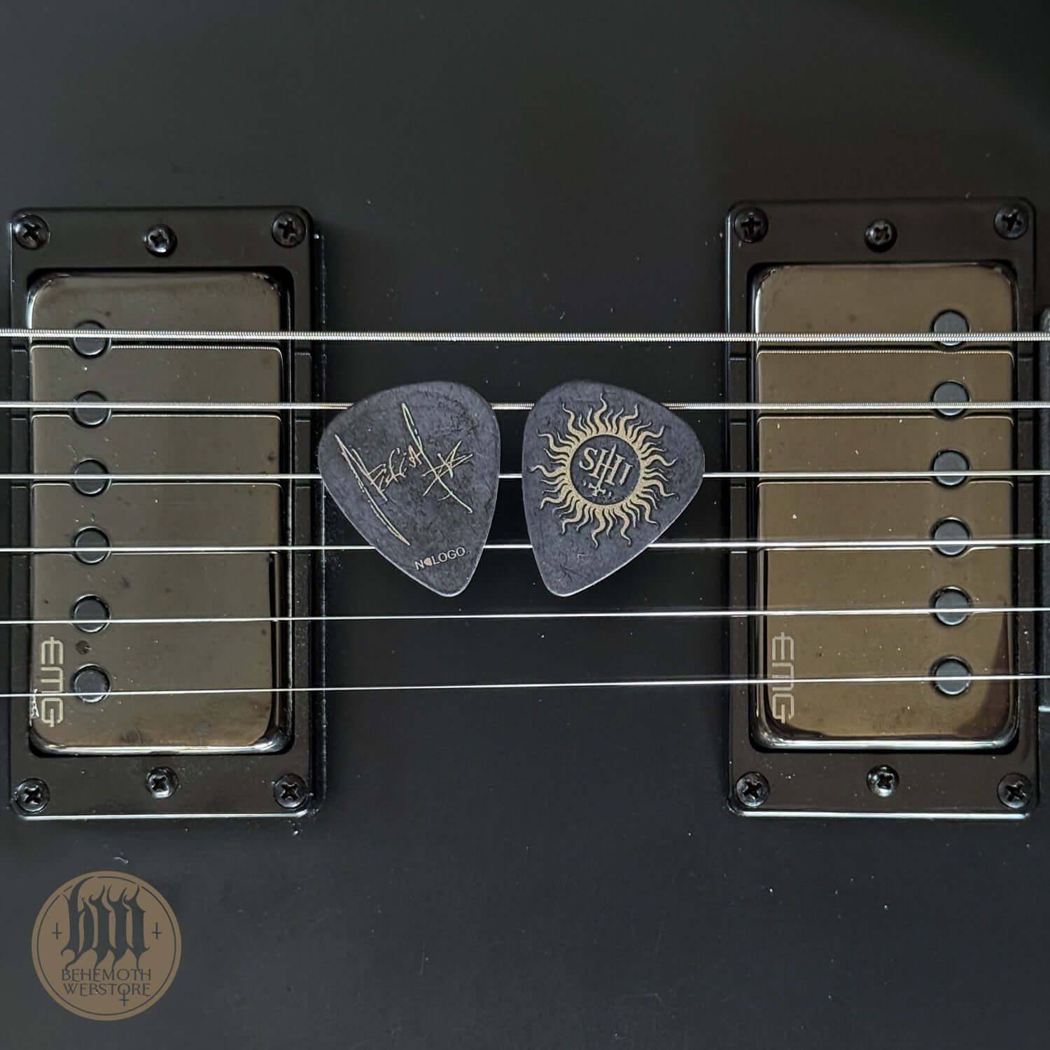 Nergal signature guitar pick with TSOG print, 1 mm thickness, placed on guitar strings.