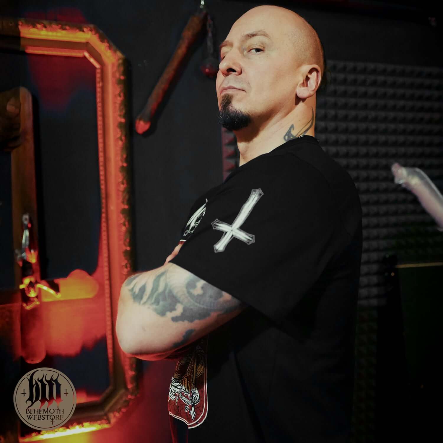 Man wearing 'The Republic Of The Unfaithful' Behemoth T-Shirt, symbolizing freedom and artistic expression in a dark, moody setting.