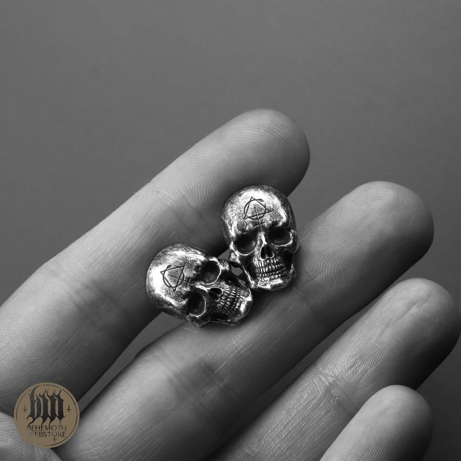 Behemoth 'Contra Skull' sterling silver skull cufflinks handcrafted with oxidized finish, displayed on fingertips for detail.